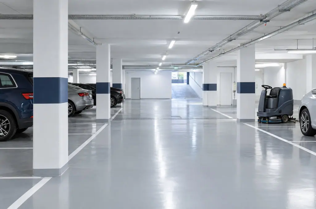 Un parking souterrain au sol époxy fraîchement lavé, autolaveuse garée